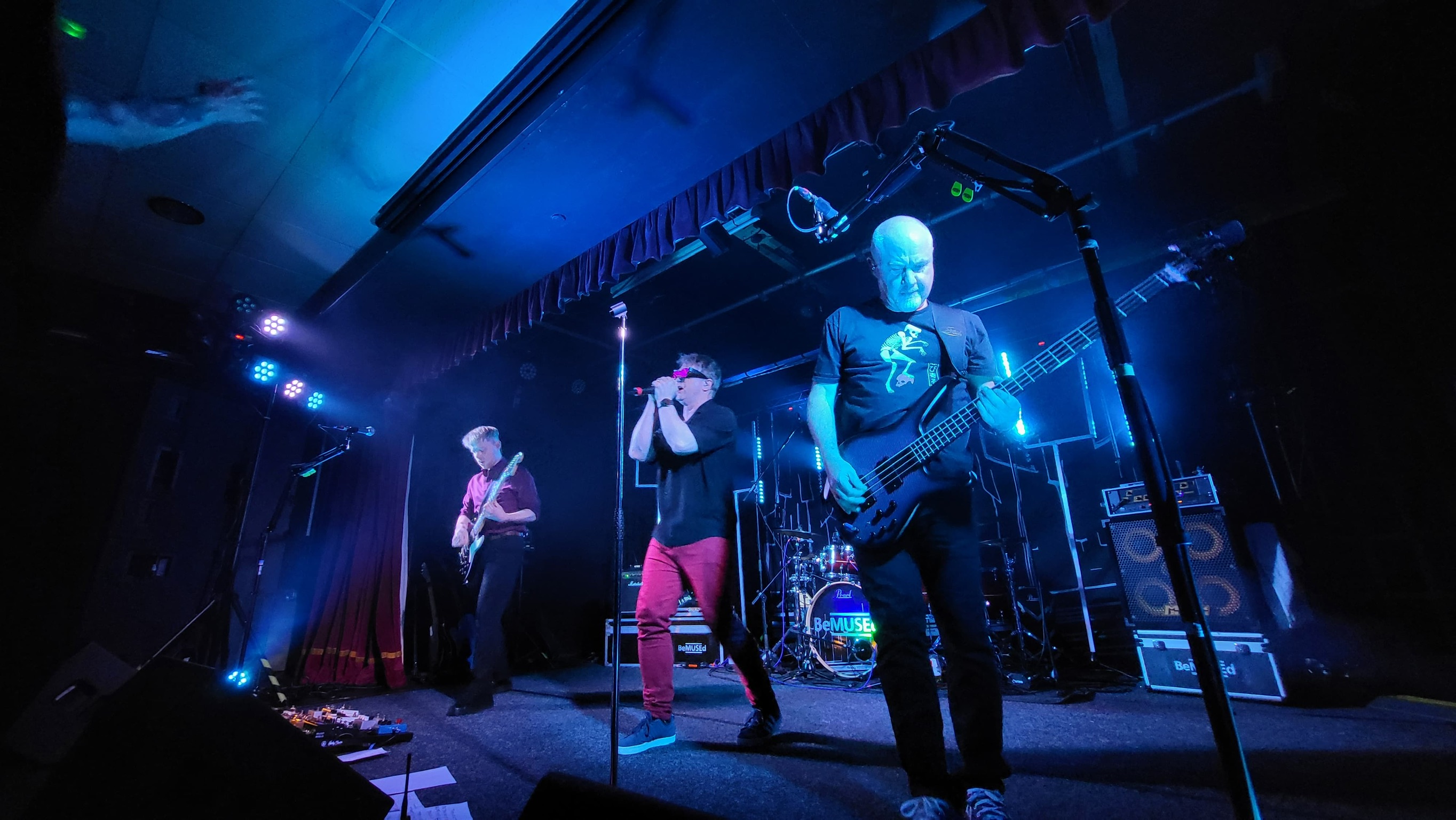 Full band shot with blue lighting, bassist featured prominently